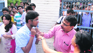 PGI staff check a candidate at an examination centre in Sector 22, Chandigarh, on Sunday