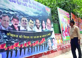 A man looks at a huge hoarding of BJP showing all the seven winning candidates at the state party office in New Delhi on Sunday