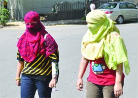Girls cover themselves with scarves to protect from scorching heat as the temperature rises to 38 C in New Delhi on Monday