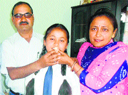 Class X topper Diksha Sharma being offered sweets by her parents and school principal on Monday. 