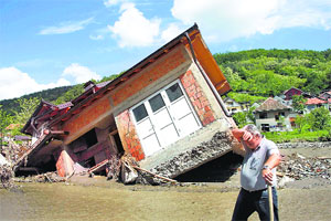 A man walks past a tilted house in a village near Belgrade on Monday.