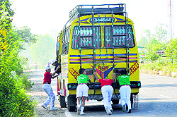 Students of Army School push a school bus after it develops a technical snag in Kathua district