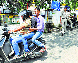 Police personnel remain mute spectators to traffic rule violations by three youths on the College road in Dharamsala on Tuesday
