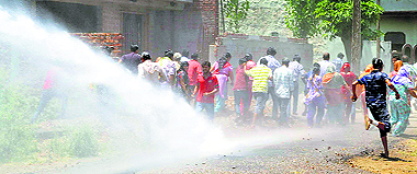 Police use a water cannon to disperse protesters; (below right) a local resident pleads for mercy; and (below left) another resident who suffered injuries on his fractured leg during the lathicharge
