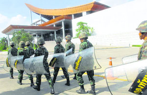 Armed with shields that read army, Thai soldiers march in line to provide security outside a meeting hall of the Army Club in Bangkok on Wednesday.