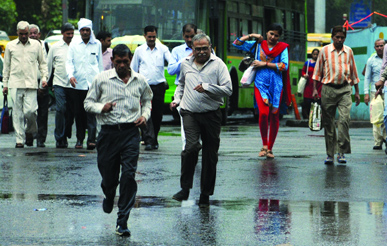 People run to save themselves from rain near ITO in New Delhi on Friday. Rain brought relief to the Delhiites, settling temprature at 39.8 C.