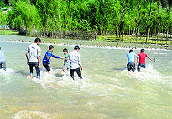 People cross a nullah in Shumriyal village of Kupwara