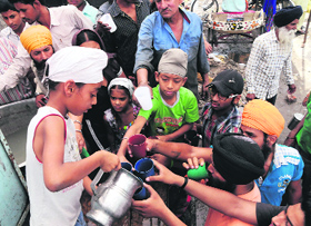 A child distributes sweet water at a chhabeel to quench the thirst of residents in Amritsar on a hot Sunday afternoon.