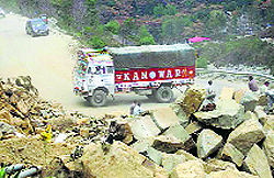 An overloaded truck plies on a narrow road