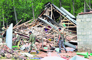 Army and police personnel look for ammunition in the debris of the house razed during a gunfight at Nowpora village in Kulgam district on Sunday.