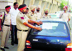 A policeman pastes a warning notice on a car wrongly parked outside a school in Mandi Ahmedgarh