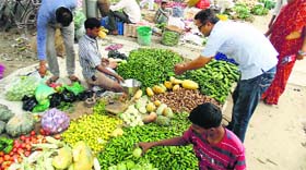 People make purchases at a weekly vegetable market near the railway overbridge in Abohar on Sunday.