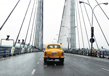 A yellow ambassador taxi crosses the Vidyasagar Setu Bridge in Kolkata on Monday. Hindustan Motors has stopped the production of the iconic Ambassador, a car that was long the choice of Indian officialdom, citing weak demand and lack of funds.
