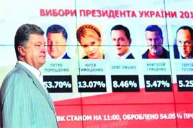 Petro Poroshenko who is leading in the prez poll results walks in front of screen displaying results of the presidential poll in Kiev