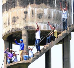 Members of the 108 Ambulance Employees Association protest on a water tank at Phase VI in Mohali on Tuesday.