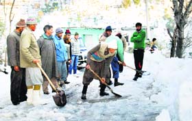 Labourers clearing snow from the Mughal Road in Poonch district on Tuesday.