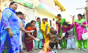 Members of the District Mahila Congress burn Malti Thapar's effigy in Ludhiana on Tuesday.