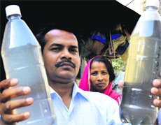 A resident of Aman Nagar shows bottles of dirty water.
