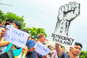 Demonstrators hold up signs during a protest against military rule at Victory Monument in Bangkok on Tuesday.