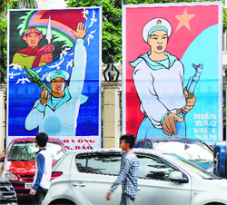 People walk past propaganda billboards featuring Vietnams grit to defend its coastal waters, in Hanoi on Tuesday