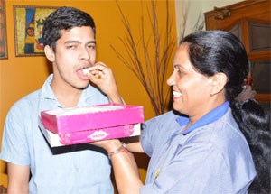 Ashwini Kumars mother, Saroj, offers him sweets after he scored 80% in the Class XII exams in Panchkula. She works as a maid in The Gurukul, Sector 20.