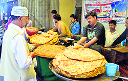 Traditional treat: Vendors prepare parantha with halwa in Srinagar on Thursday. Large paranthas along with halwa is sold outside mosques and shrines in Kashmir