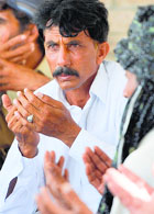 Mohammad Iqbal prays along with relatives for his wife Farzana in Chak on Friday.