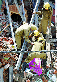 Rescue workers pull out a body from the debris of a three-storey under-construction building at Sadar Bazar in Delhi on Sunday