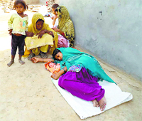 A woman and her newborn lying on a road outside a delivery hut of the Primary Health Centre at Kulan village in Fatehabad district. 