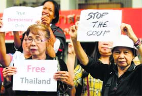 Protesters hold up signs during a brief protest against military rule at Thammasat University in Bangkok on Sunday