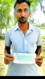 A villager shows a compensation cheque for Rs 18.75 at Gurusar village.