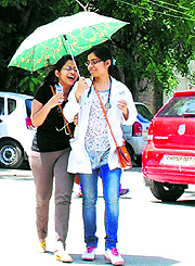 Girls walk under the shade of an umbrella on a hot summer afternoon in Amritsar on Tuesday