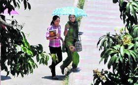 Students use an umbrella to protect themselves on a hot sunny day in Chandigarh on Tuesday
