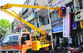 A crane removes illegal hoardings at the Phase V market in Mohali on Tuesday