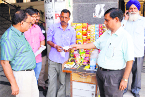 Officials of the Health Department challan a vendor for selling tobacco products without displaying a warning in Ludhiana on Tuesday.