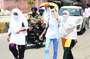 Girls cover their faces to protect themselves from the scorching heat in Bathinda on Wednesday.