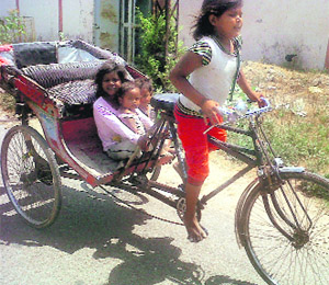 A barefoot child carries her three siblings on a hot summer day in Bathinda on Wednesday.
