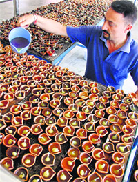 A Kashmiri Pandit pours oil in lamps on the eve of Kheer Bhawani Mela in Jammu on Thursday.