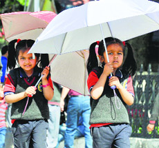 Students walk in the shade of umbrellas to protect themselves from the scorching heat in Shimla on Friday.