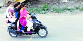 Flouting rules, a Kashmiri girl along with two others riding pillion, drives a scooter without wearing a helmet in Srinagar on Friday.