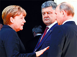 German Chancellor Angela Merkel (L), Ukrainian President-elect Petro Poroshenko and Russian President Vladimir Putin (R) in conversation at the D-Day event in France on Friday.