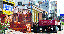 Labourers unload bricks at a construction site in Amritsar on Saturday
