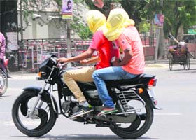 Motorcyclists cover their faces to protect themselves from the scorching heat in Bathinda on Saturday