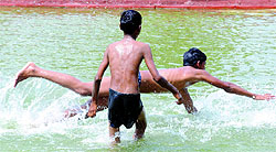Children play in a pond during a hot afternoon in New Delhi on Saturday. Heat wave conditions prevail in the city as the temperature remains near 46 C.