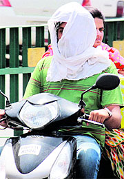 A scooterist covers his face to protect himself from the heat in Bathinda on Sunday.