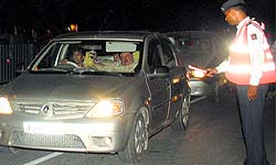 A traffic policeman signals a car to stop for checking at a drunken driving naka