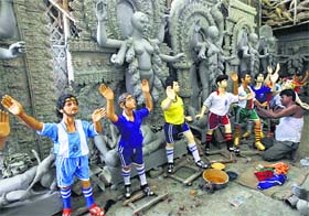 Indian artisan Sukumar Rudra Pal gives finishing touches to clay models of soccer players in a workshop in Kolkata on Monday.