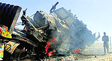 An Afghan policeman stands near a burning NATO supply truck in Behsud district of Jalalabad on Monday. 