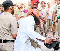 Policemen detain devotees who were trying to resist the demolition.