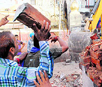 A devotee brandishing a brick to prevent the JCB machine from demolition.